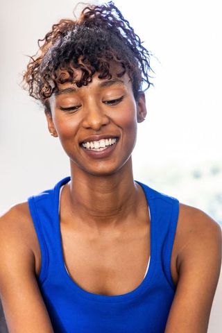 African american woman smiling while looking down in royal-blue tank lifestyle portrait