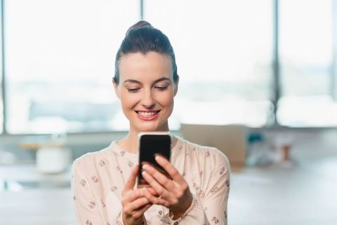 Smiling Woman Using Smartphone in Office Setting
