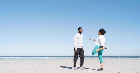 Couple Stretching and Chatting on Beach During Outdoor Fitness Routine