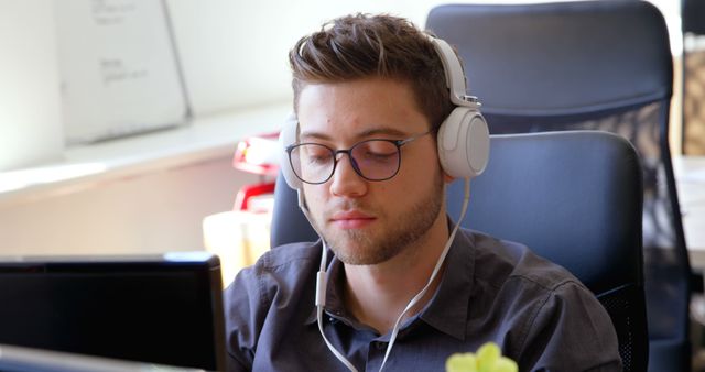 Young Professional Wearing Headphones Working at Desk in Office - Download Free Stock Images Pikwizard.com