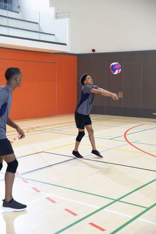 African american teenage boys practicing volleyball forearm pass in indoor gymnasium
