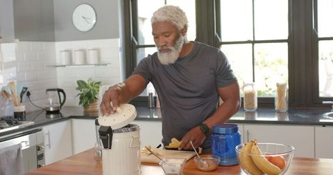 Senior african american man making healthy snack in modern kitchen