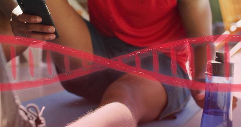 Man using smartphone after home workout on mat with water bottle and red dna helix