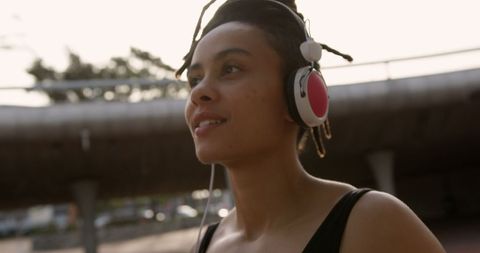 Smiling Woman Enjoying Music with Headphones in Urban Environment