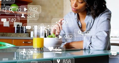 Using tablet at kitchen counter while eating salad and juice with social media overlays