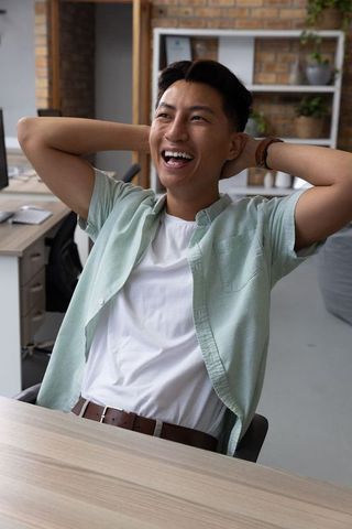 Cheerful Young Man Relaxing at Modern Office Desk