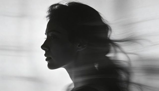 Monochrome wind-swept female profile with rim light, flowing hair and motion blur