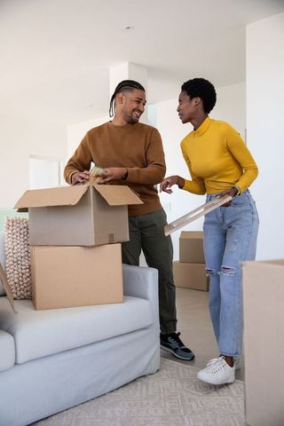 Cheerful couple unpacking moving boxes in modern living room