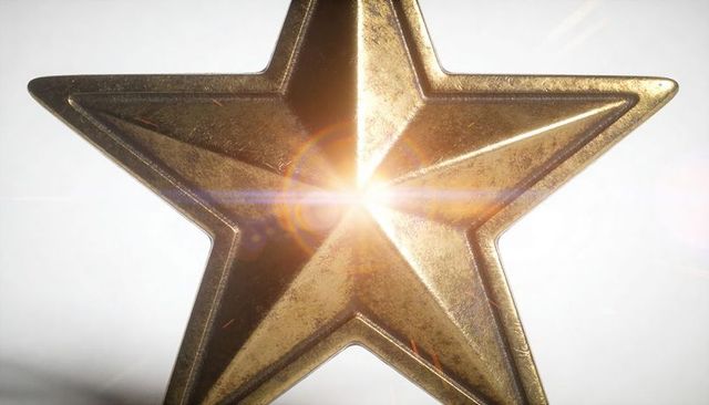 Golden beveled star medal reflecting bright lens flare with patina and scratches