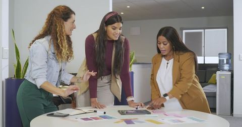 Diverse female team collaborating around roundtable with tablet and color swatches