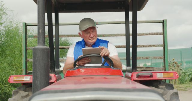 Senior farmer can be seen using a digital tablet while driving a tractor on the farm. This scene represents the integration of modern technology in traditional farming practices and highlights the importance of staying updated with digital tools in agriculture. Ideal for use in themes related to agribusiness, modern farming techniques, elderly people embracing technology, and rural life.