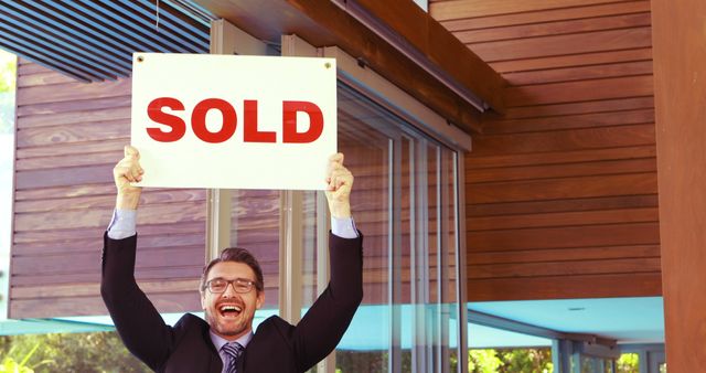 Happy real estate agent holding 'Sold' sign outside modern house - Download Free Stock Images Pikwizard.com