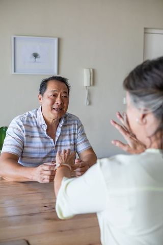Senior Couple Communicating Over Rustic Table at Home