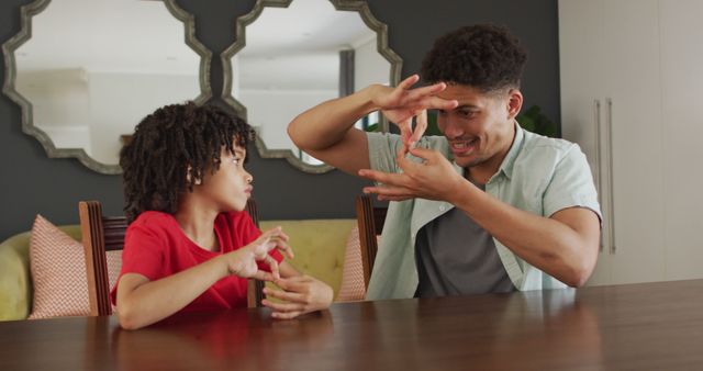 Happy biracial man and his son using sign language. domestic life, spending time at home.