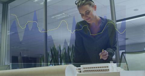 Businesswoman Analyzing Architectural Model with Data Overlay