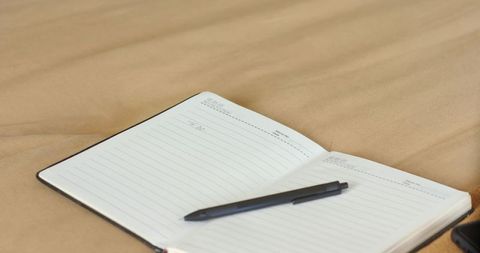 Open Notebook with Pen on Beige Bed Creating Relaxing Workspace