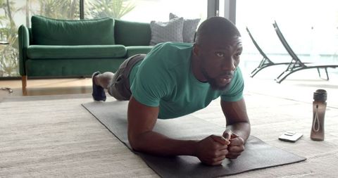 Man practicing forearm plank in modern living room