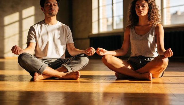 Couple practicing meditation and mindful breathing in sunlit yoga studio