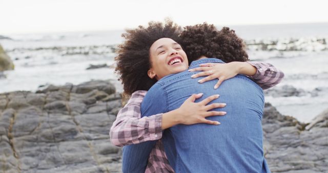 African american woman hugging her husband on the rocks near the sea. love and relationship concept