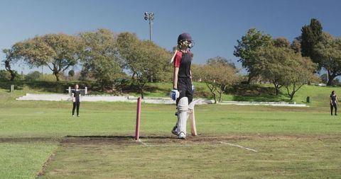 Woman playing cricket seen batting on sunny day