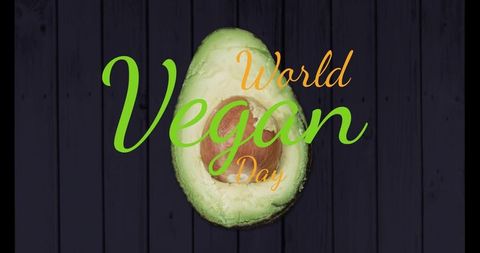 Celebrating world vegan day with avocado half on dark wood planks typography