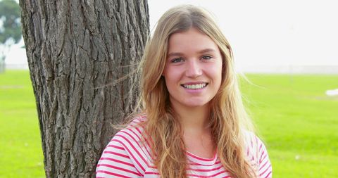 Happy Young Woman Smiling Near Tree in Park