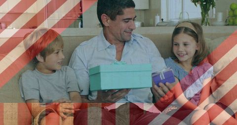 Father bonding with children while giving gifts on sofa