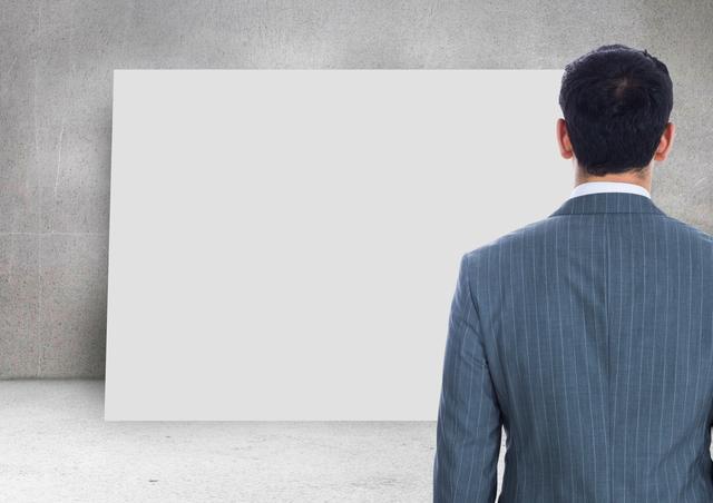 Businessman in a suit looking at a blank card on a wall. Ideal for concepts related to business planning, strategy, presentations, and corporate decision making. Can be used in articles, blogs, and marketing materials to illustrate themes of contemplation, professional planning, and business strategy.