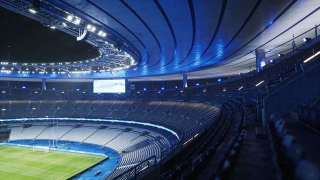 Empty stadium bowl glowing with blue led ribbon, illuminated roof truss and video screen
