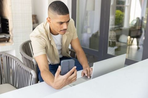 Working remotely on patio table using laptop and smartphone in modern sunroom