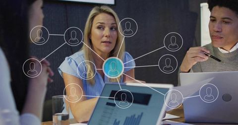 Female leader speaking with team at table, collaborating on strategy and data analytics