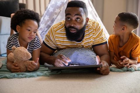 Father and Children Relaxing Indoors with Tablet and Toy