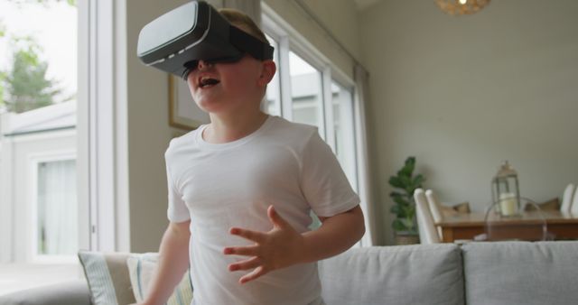 This image shows a young boy immersed in virtual reality, expressing excitement. The relaxed home environment suggests a family-friendly setting for innovative technologies. This image is perfect for articles on children's tech toys, VR gaming advertisements, or home tech innovations.