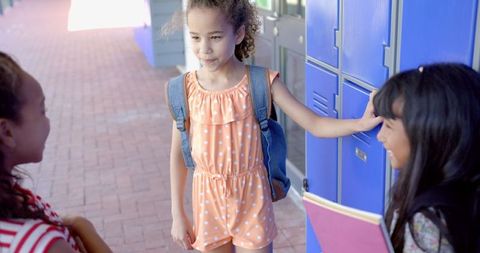 Girls Conversing at School Lockers in Colorful Outfits on Sunny Day
