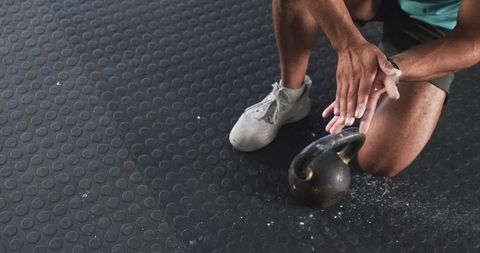 Man Preparing for Kettlebell Exercise with Chalk in Gym