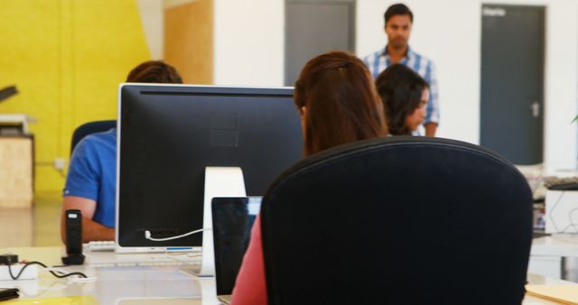 Several employees working at desks in a modern office, suggesting a focus on teamwork and productivity. Visible computer screens indicate use of technology in business setting, suitable for illustrating concepts of corporate work, collaboration, and professional environment.