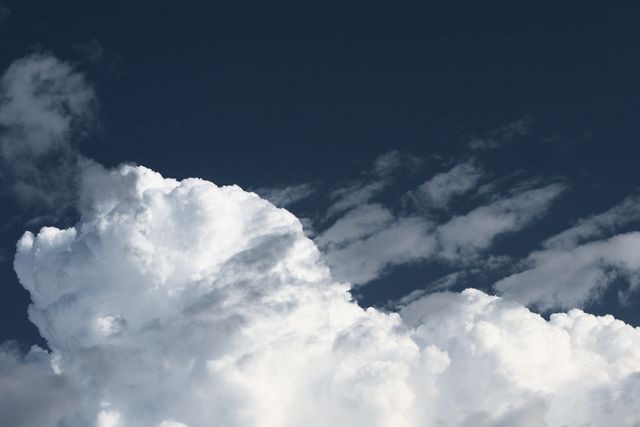 Puffy white clouds filling a dark blue sky, creating a striking contrast. This can be used in nature scenes, weather reports, desktop wallpapers, or backgrounds for serene and peaceful imagery.