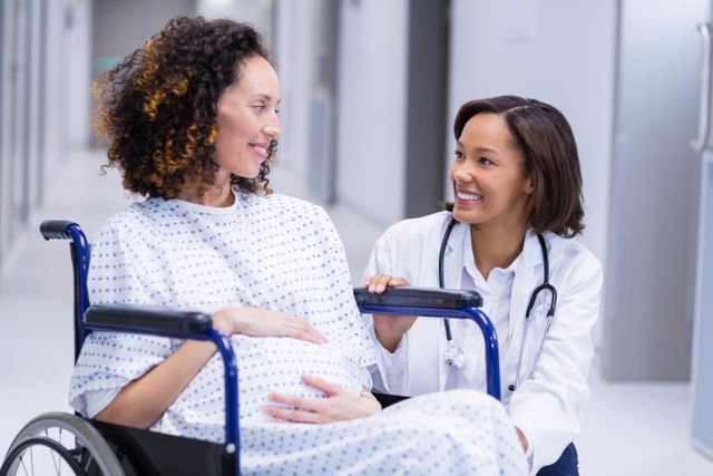 Doctor comforting pregnant woman in corridor of hospital