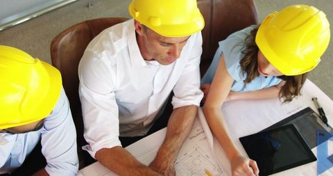 Architects in Team Collaboration Reviewing Blueprint in Office