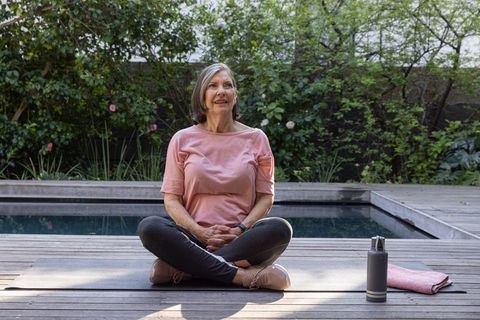 Senior Woman Meditating Poolside in Peaceful Outdoor Setting