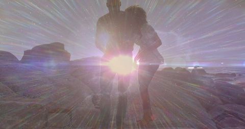 Diverse couple embracing on rugged coastline under dramatic sun flare and cinematic glow