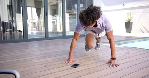 Young Man Exercising with Smartphone Outdoors Near Pool