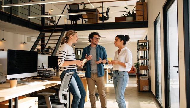 Casual office team collaborating and brainstorming with sticky notes in modern loft workspace
