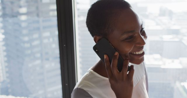 Smiling Businesswoman Talking on Phone in Office with City View - Download Free Stock Images Pikwizard.com