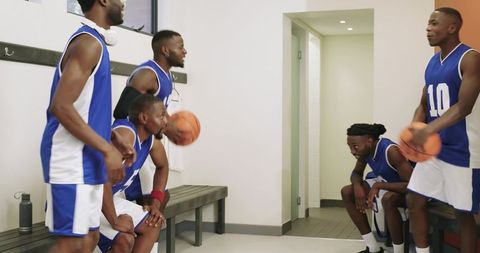 Basketball team bonding in locker room preparing for game while teammates strategizing
