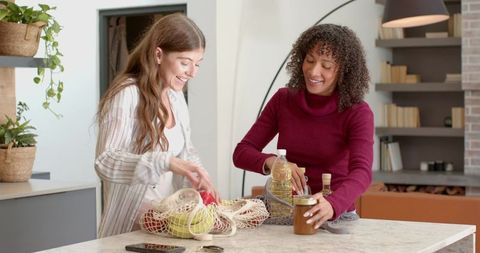 Diverse friends unpacking groceries in modern kitchen