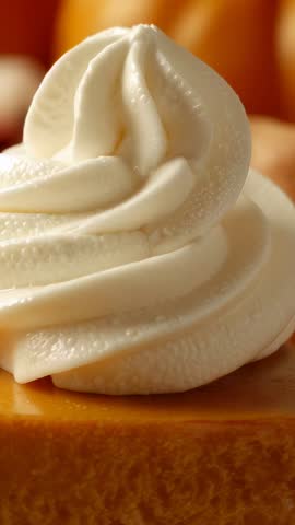 Vertical close-up panning whipped cream swirl on pumpkin pie slice with autumn gourds