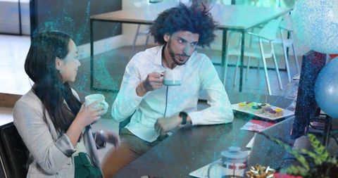 Coworkers sharing coffee and cupcakes while chatting in modern bright office break lounge