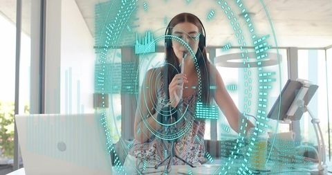 Young woman speaking into microphone wearing headphones at standing treadmill desk hud