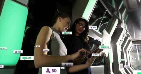Women analyzing data metrics in futuristic tech corridor